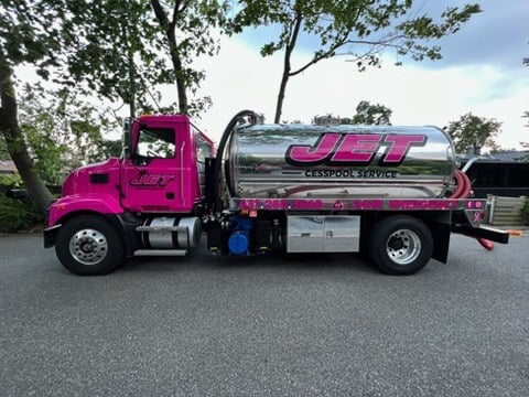 Side view of a JET Cesspool Service pump truck on a tree-lined street