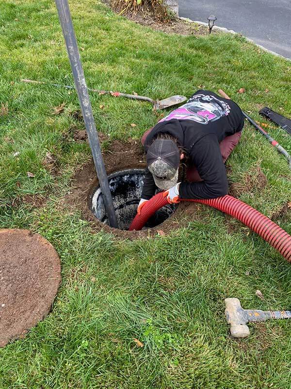 JET technician in a pink JET shirt pumping a residential cesspool