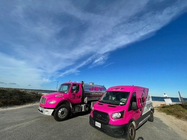 JET pink pump truck and service van parked by a Long Island beach