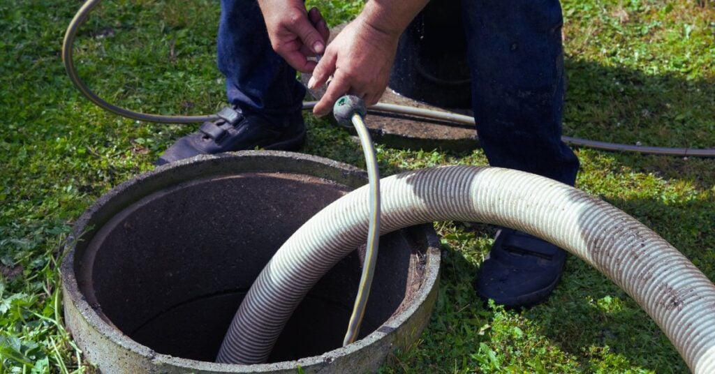 Pumping hose lowered into an open septic tank